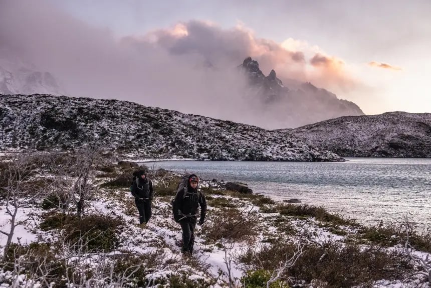 Two hikers walking near a lake in Torres del Paine National Park in winter